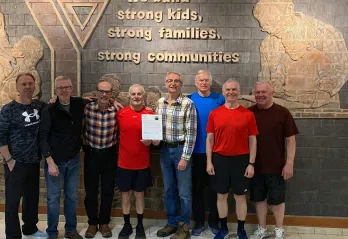 A group of eight older adults standing together smiling