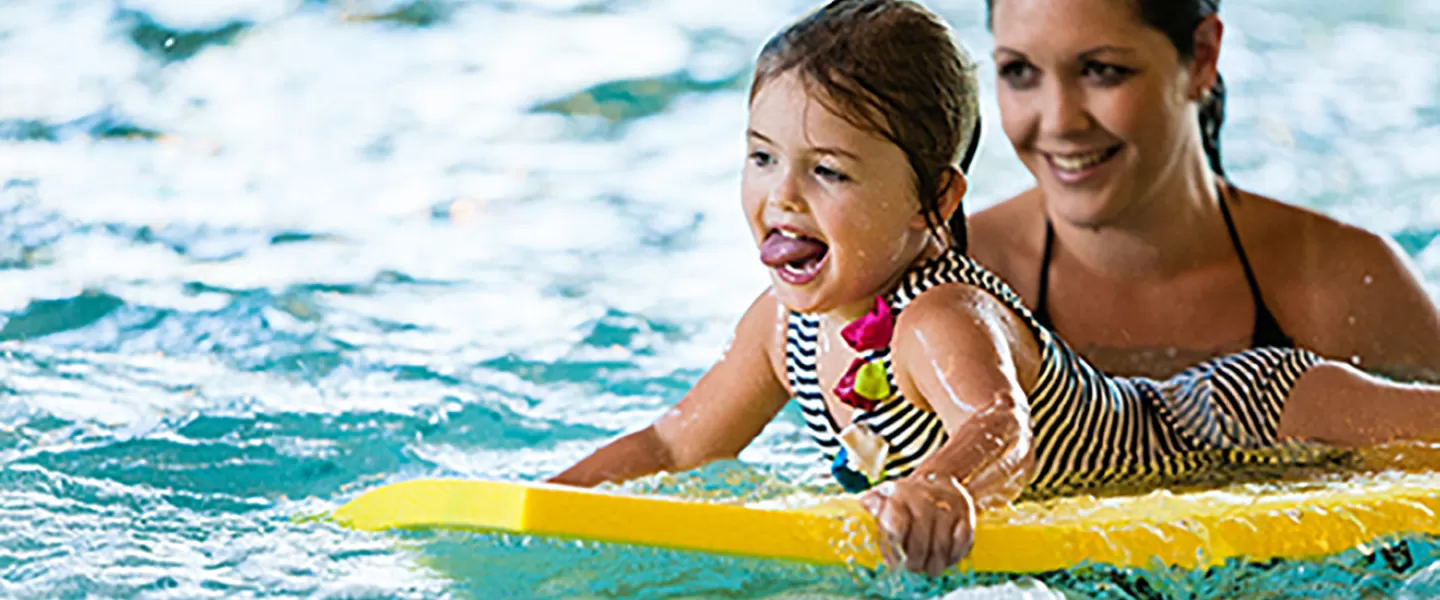 child smiling while riding on flutter board in pool