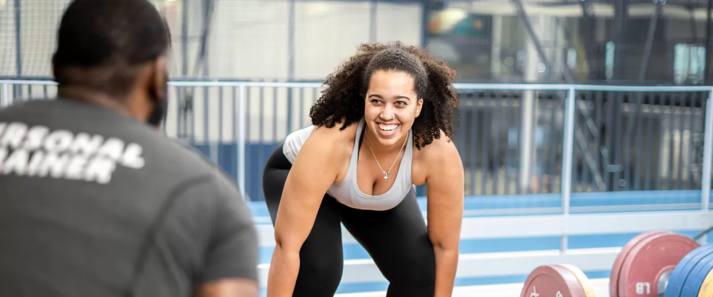 a girl dead lifting weights with a personal trainer