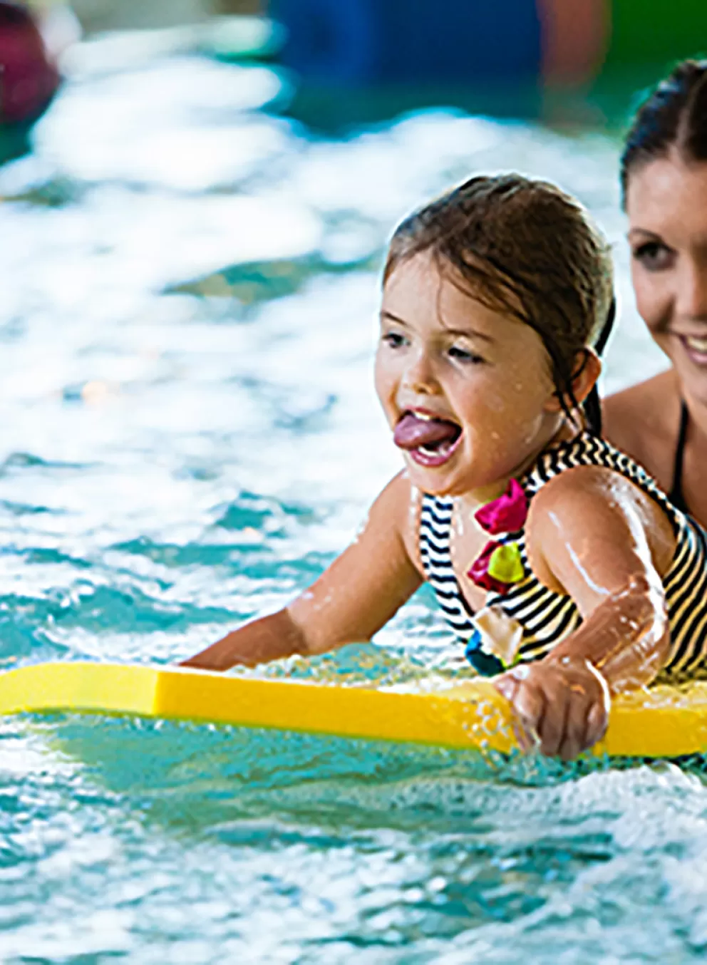 child smiling while riding on flutter board in pool
