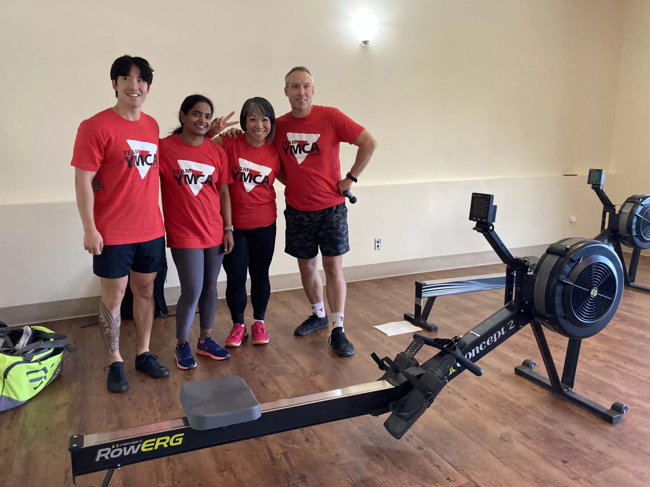Team YMCA poses with rowing machines, donning red YMCA t-shirts and ready for the action.