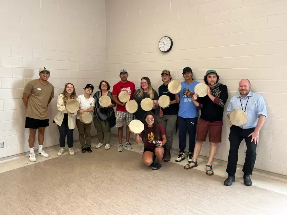 YMCA Calgary staff took part in a drum-making activity, showing off their drums with smiles.