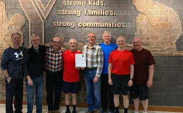 A group of eight older adults standing together smiling